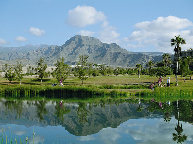 German Golf Academy Golfmitgliedschaften Golfplatz mit Bergen im HIntergrund und Wasser im Vordergrund